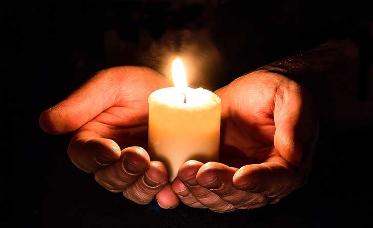 Hands cupping a candle 