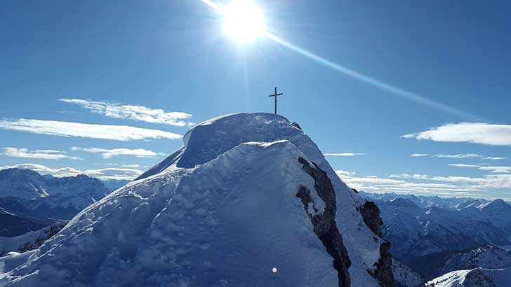 Cross on top of snow covered mountain